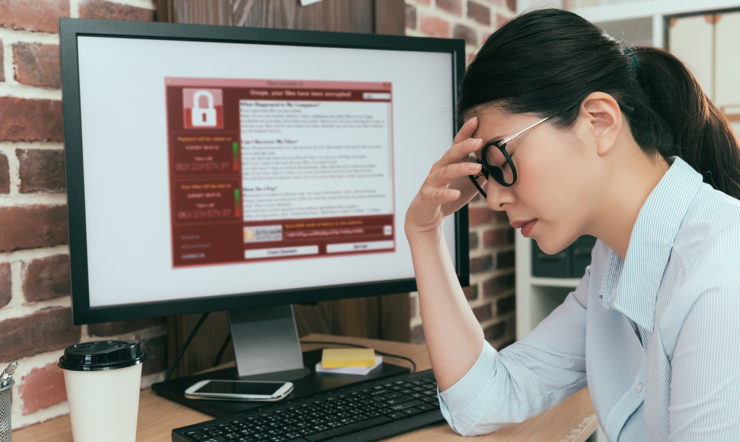 Vrouw die met de handen in de haren zit en merkt dat haar computer gehackt is.