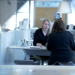 Kaksi henkilöä istuu pöydän ääressä palaverissa