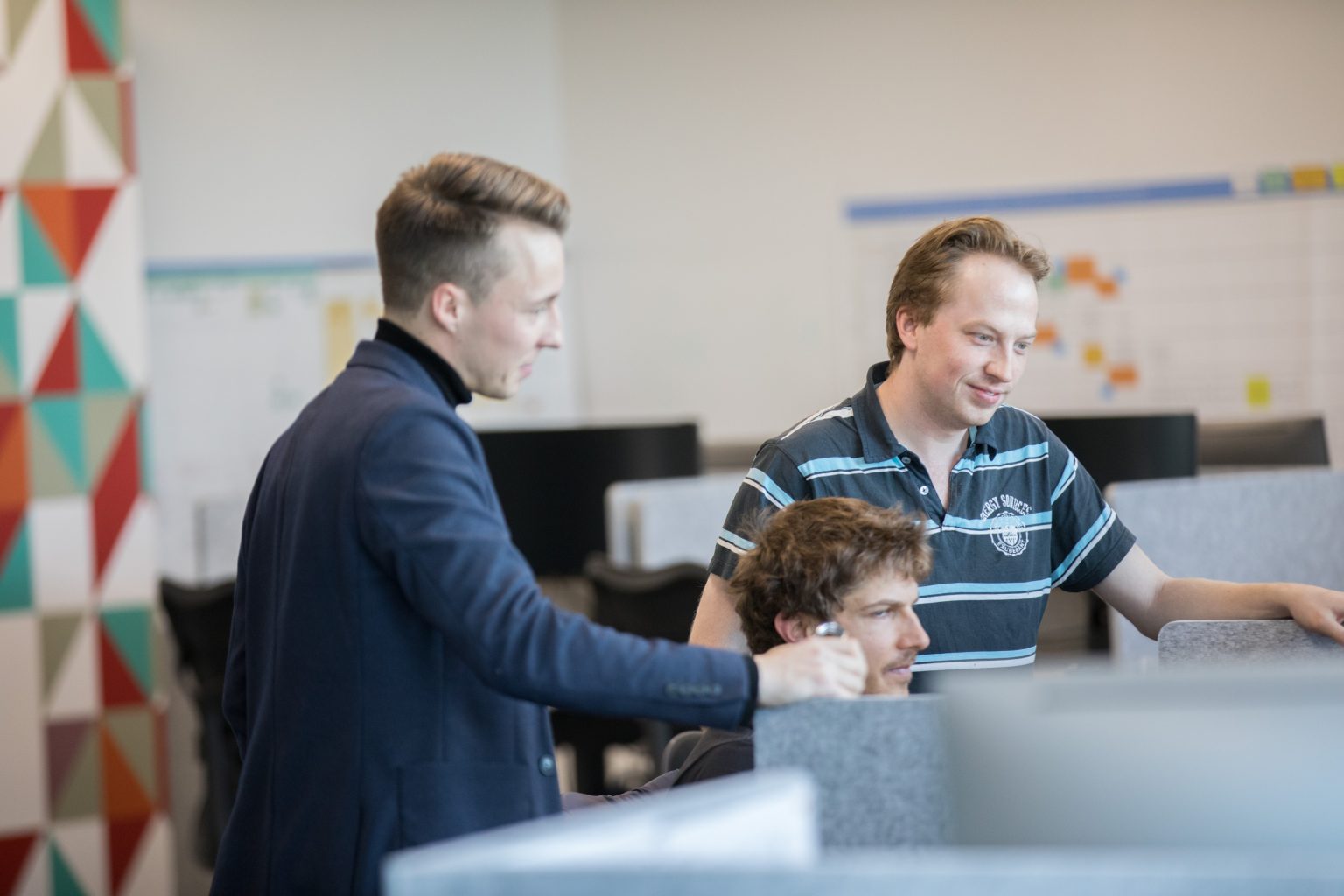 Three men crowded around a computer