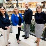 3 women and 1 man standing on a balcony