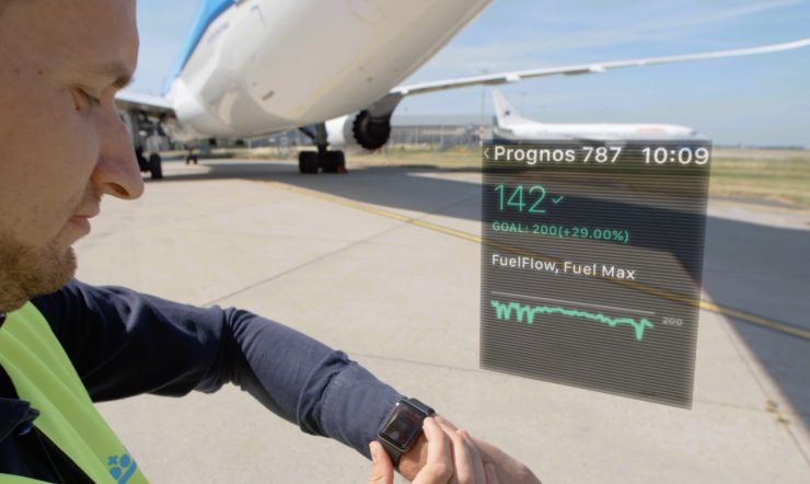 Guy standing next to plane looking at Smartwatch to check reporting.