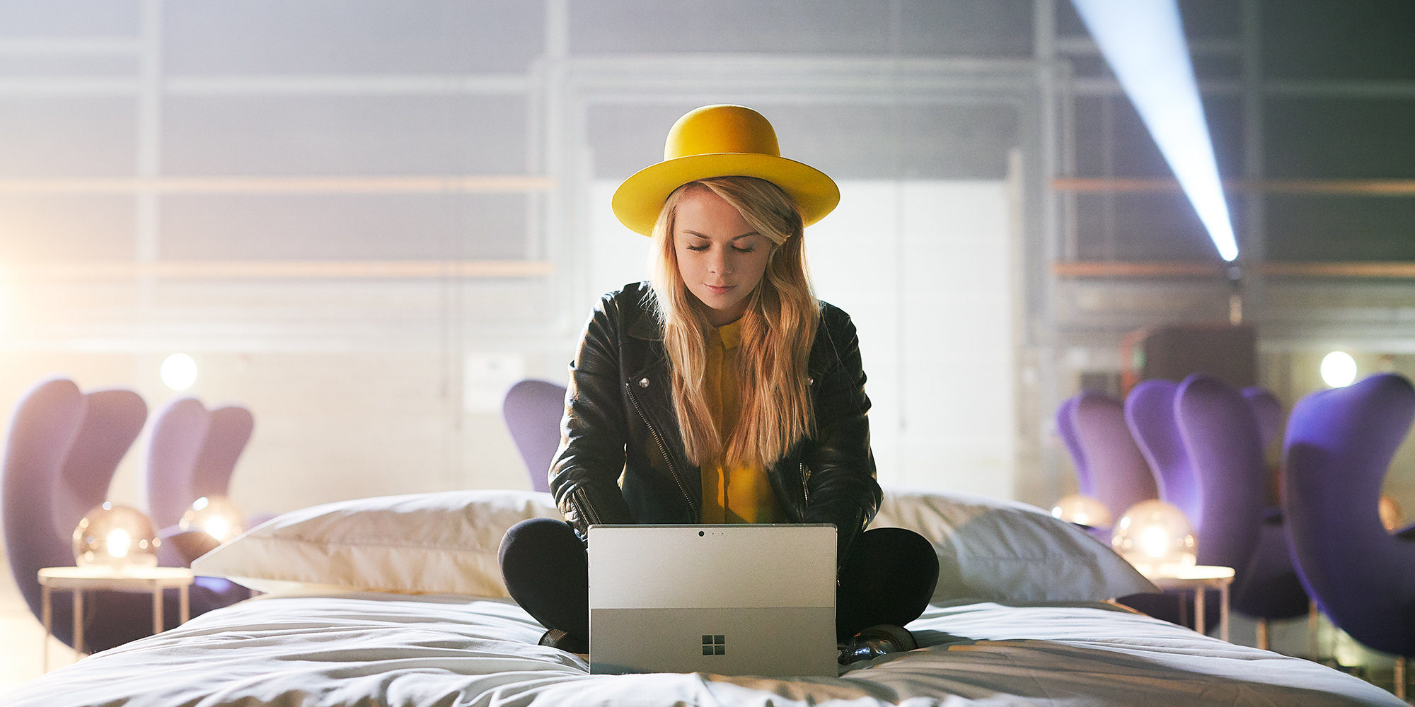 A woman with a yellow hat working on a Surface