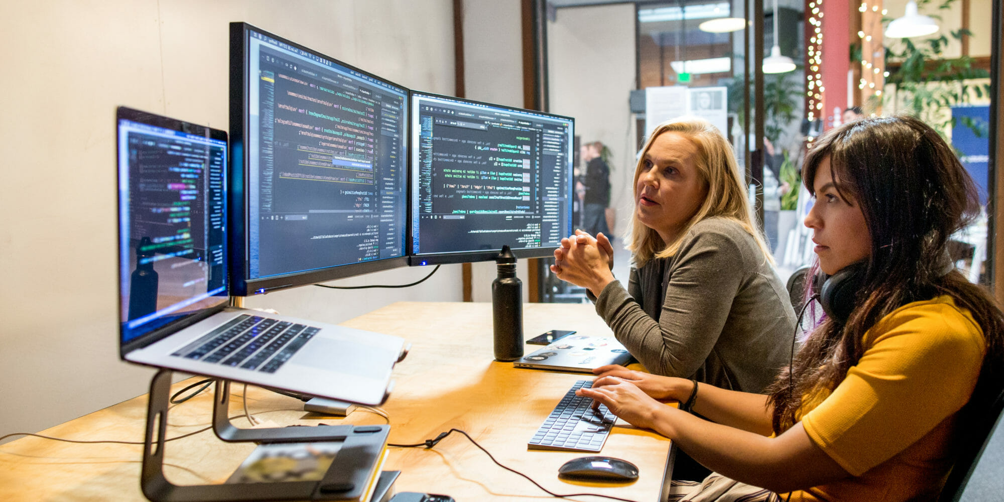 nainen, joka istuu pöydässä kannettavan tietokoneen avulla