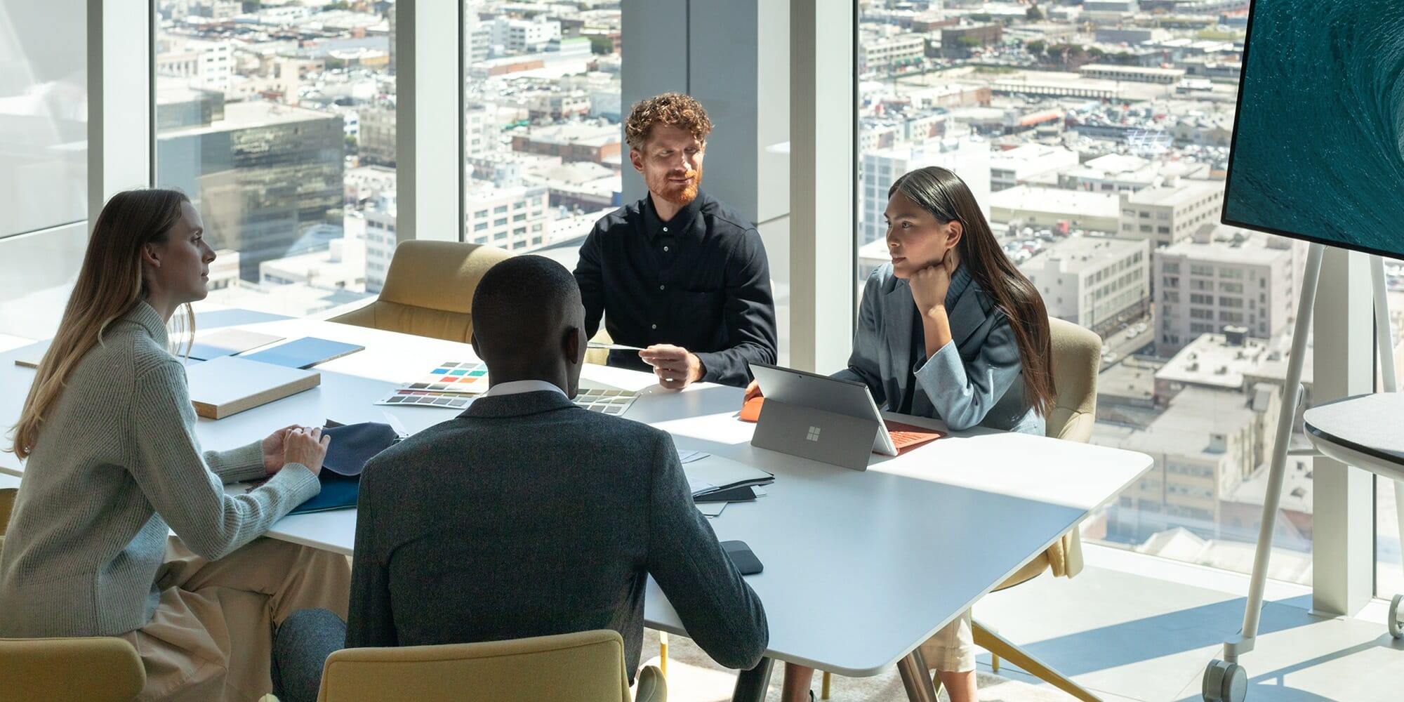 ryhmä ihmisiä, jotka istuvat pöydässä kannettavan tietokoneen avulla