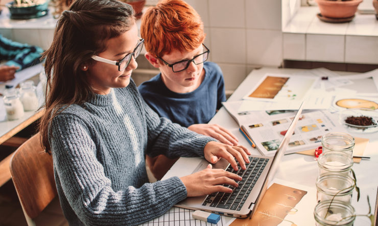 Duas pessoas a trabalharem num computador numa sala de aula