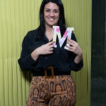 Uma mulher sorridente a agarrar na letra M