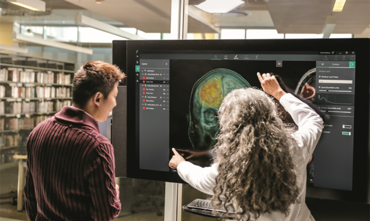 Duas pessoas analisam a imagem de um crânio humano no Microsoft Surface Hub