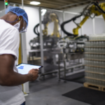 Um colaborador numa zona de carga a usar um tablet para controlar um robot a carregar paletes