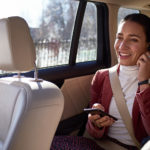 En kvinde sidder i en taxi og taler i telefon