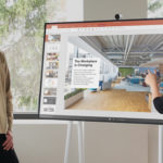 un hombre y una mujer de pie frente a un equipo Surface Hub 2S