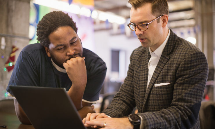 Twee mannen werken samen op een laptop