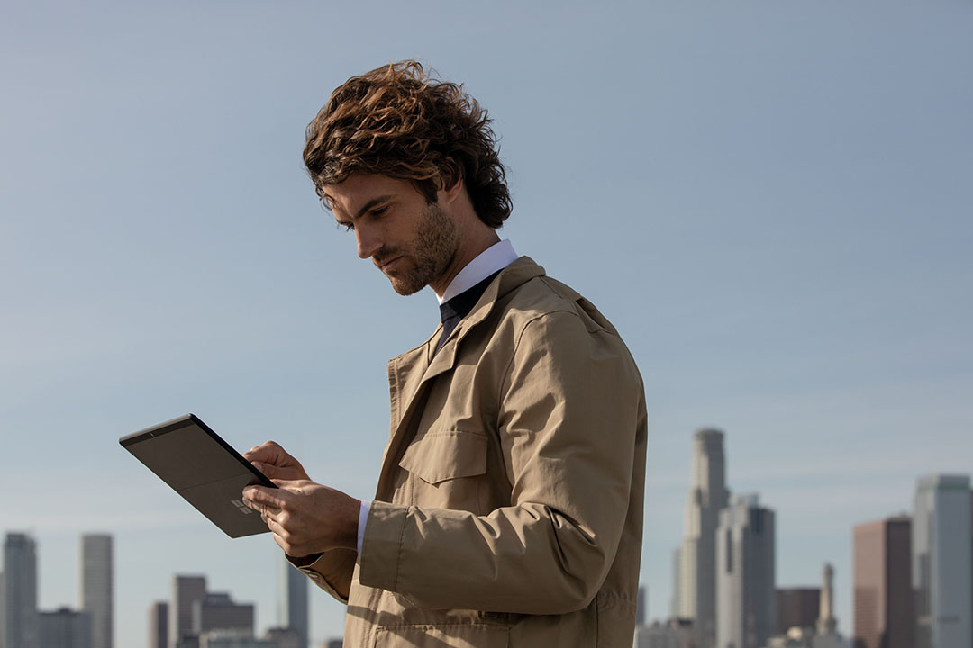 Een man staand aan het werk op een Surface pro X