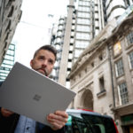 Man loopt met Surface device over straat