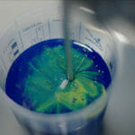et nærbillede af en flaske med blå og grøn maling