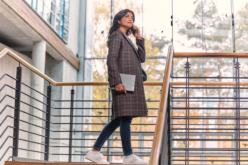 Vrouw met telefoon en Surface in een kantoorgebouw