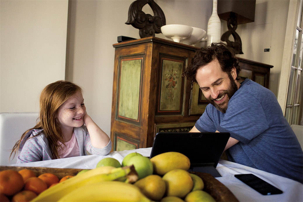Father and daughter at dining room table on laptop; Photographer: Bobo Olsson