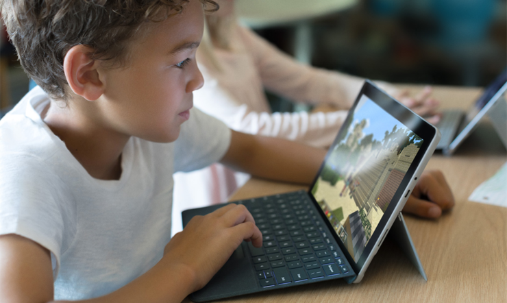 Children, students in classroom playing Minecraft on Surface Go. Contextual education.