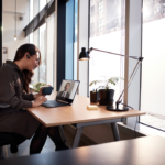 en person, der sidder ved et skrivebord med en bærbar computer på et bord