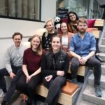 en gruppe mennesker som sitter på en benk poserer for kameraet