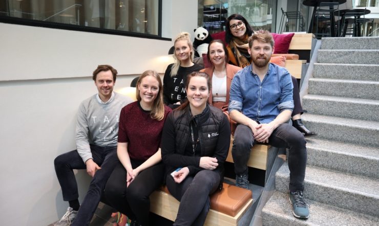 en gruppe mennesker som sitter på en benk poserer for kameraet