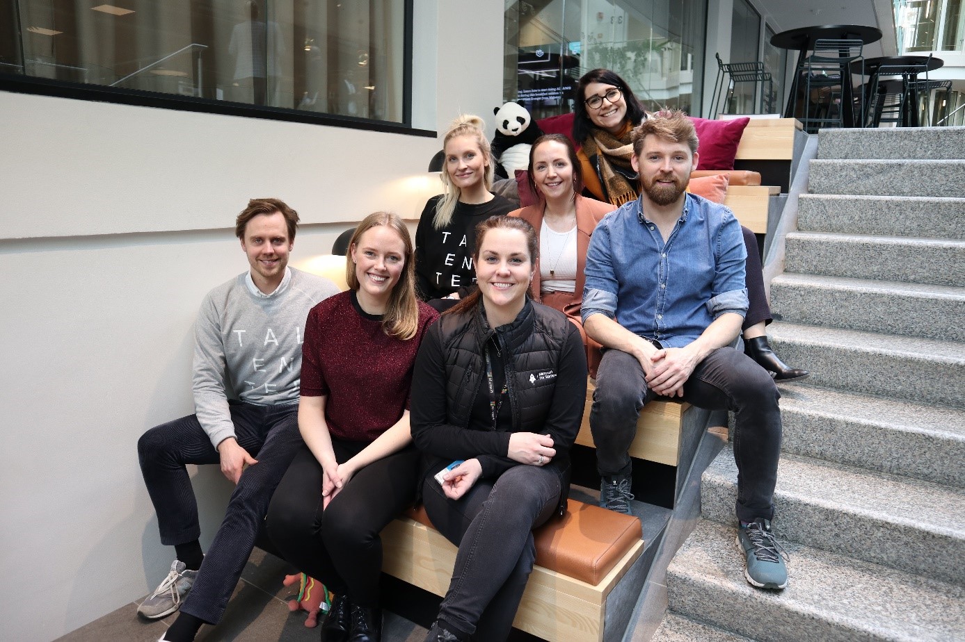 en gruppe mennesker som sitter på en benk poserer for kameraet