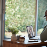 una persona sentada en una mesa usando un ordenador portátil