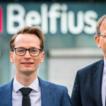 Two people wearing a suit and tie smiling at the camera