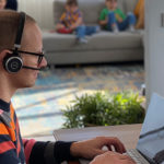 henkilö istuu pöydässä kannettavan tietokoneen