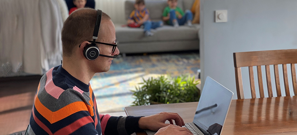 henkilö istuu pöydässä kannettavan tietokoneen