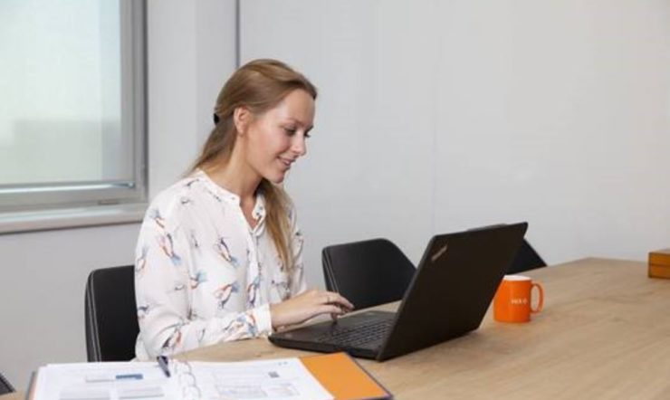 een vrouwenzitting bij een lijst die laptop gebruikt