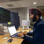 Man behind laptop and screens