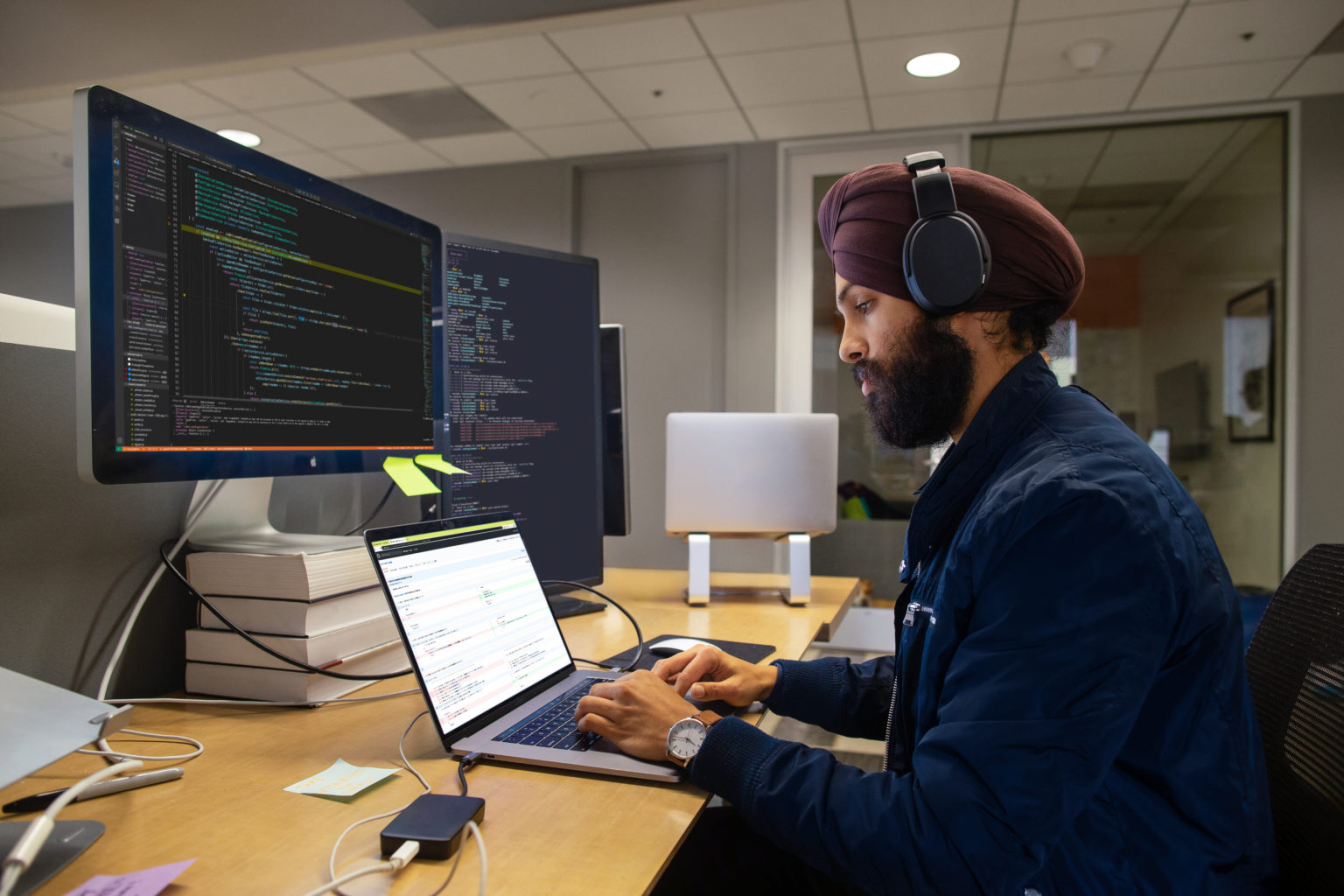Man behind laptop and screens
