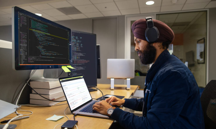 Man behind laptop and screens