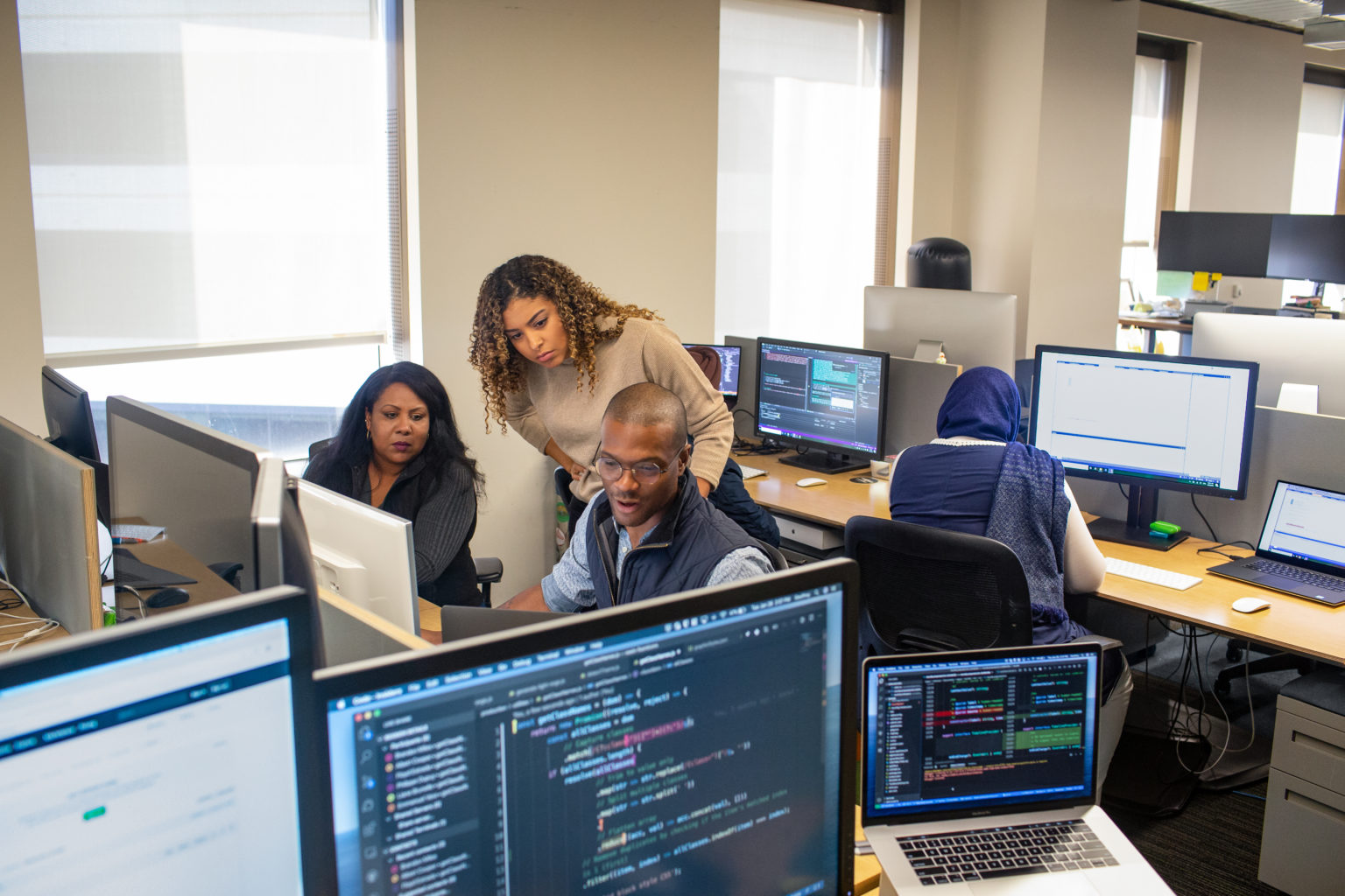 Two females, one mail behind computer screens
