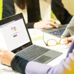 un grupo de personas sentadas en una mesa usando una computadora portátil