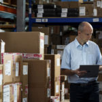 mies seisoo edessä kirjan hylly