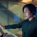 nainen, joka seisoo tietokoneen näytön edessä