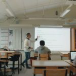 en grupp människor som sitter vid ett bord i ett rum