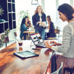 un grupo de personas sentadas en una mesa usando un portátil