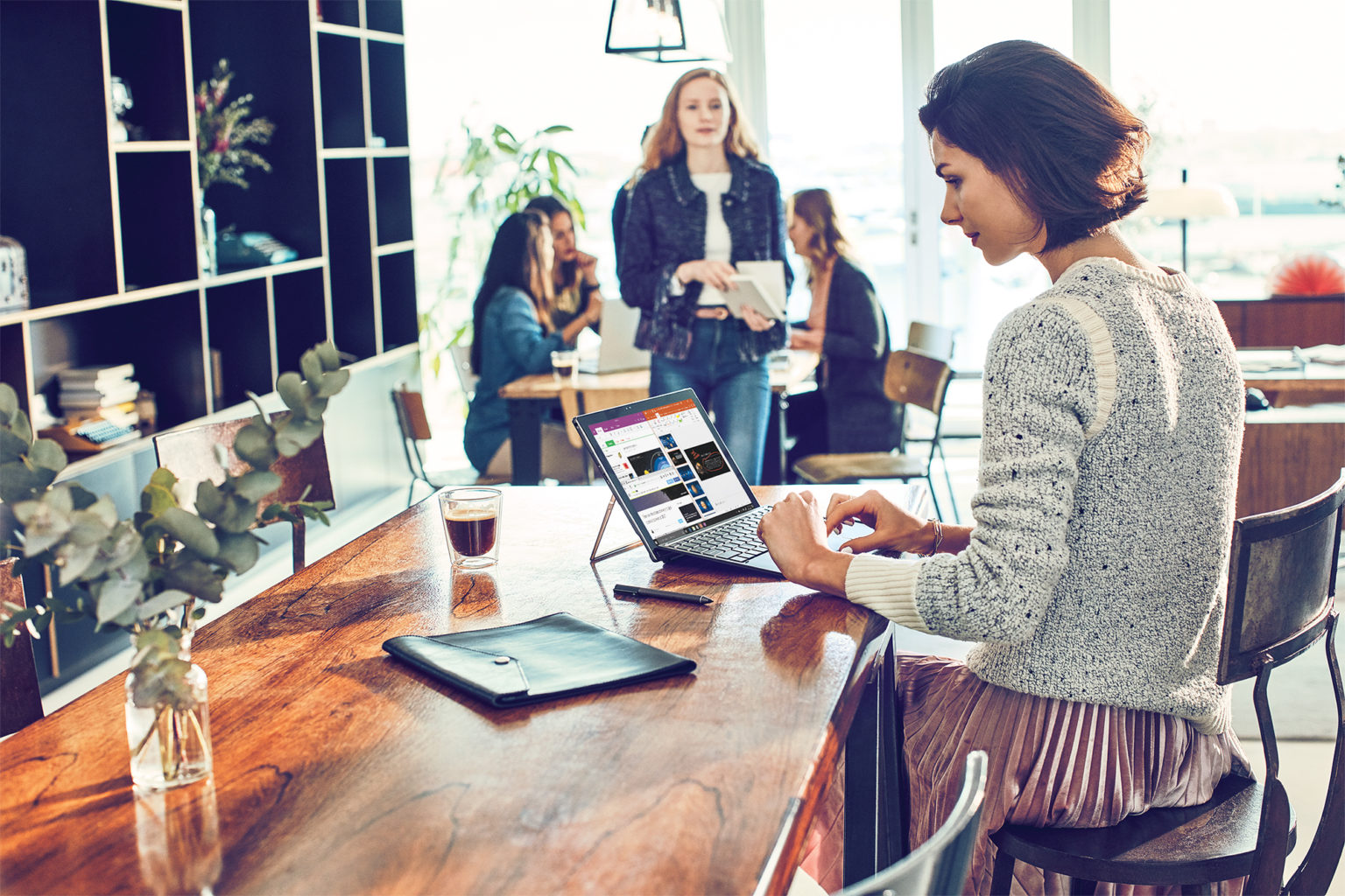 un grupo de personas sentadas en una mesa usando un portátil