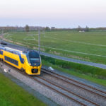 een trein die onderaan treinsporen dichtbij een gebied reist