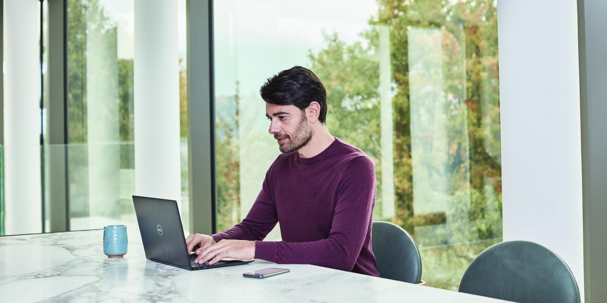 en person som sitter vid ett bord med hjälp av en bärbar dator