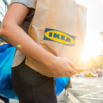a person walking down a street with an Ikea bag