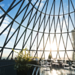 een groot gebouw met een metalen hek met 30 St Mary Axe op de achtergrond