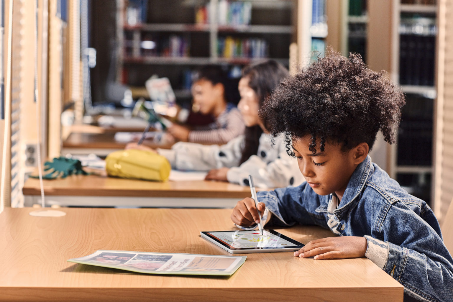 un jeune garçon s’asseyant à une table utilisant un ordinateur portatif