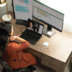 henkilö, joka istuu pöydän ääressä kannettavan tietokoneen edessä