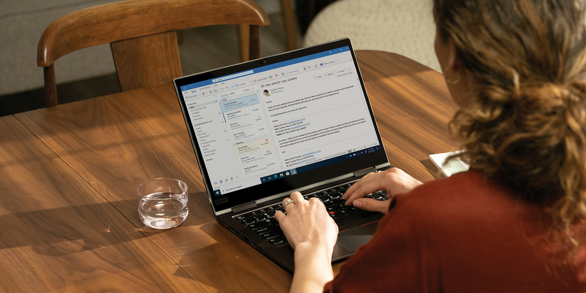 henkilö, joka käyttää kannettavaa tietokonetta ja istuu puupöydän päällä