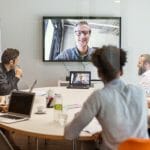 een groep mensen die bij een bureau voor een venster zitten