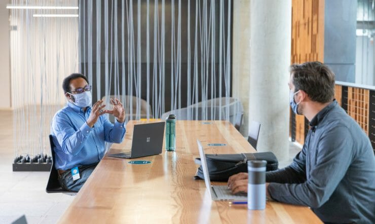 a group of people sitting at a table using a laptop