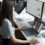 uma pessoa sentada em uma mesa na frente de um computador portátil